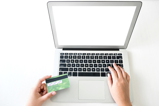 Business woman holding credit card entering security code and using laptop computer, online shopping concept.