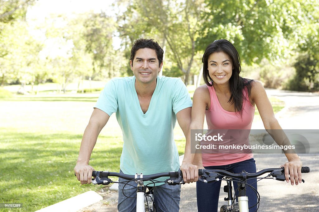 Young Couple Riding Bikes In Park  Exercising Stock Photo