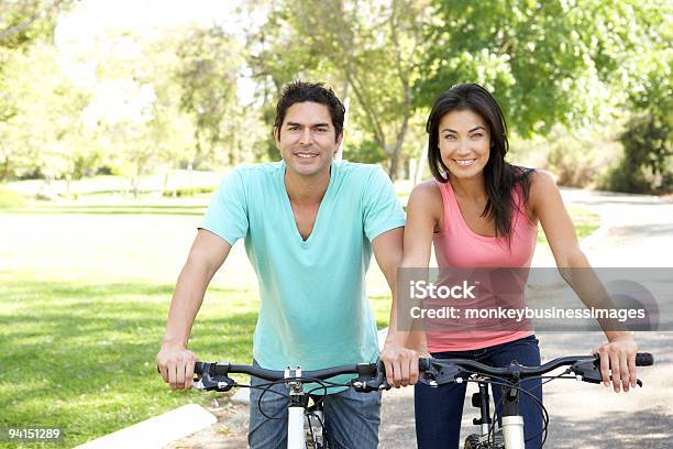 Young Couple Riding Bikes In Park Stock Photo - Download Image Now - Exercising, 30-39 Years, Healthy Lifestyle