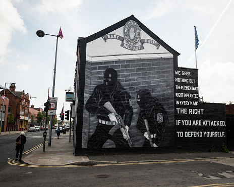 A woman walks past a political mural in Belfast, Northern Ireland