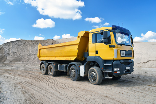 Truck transports sand in a gravel pit - gravel mining in an open pit mine