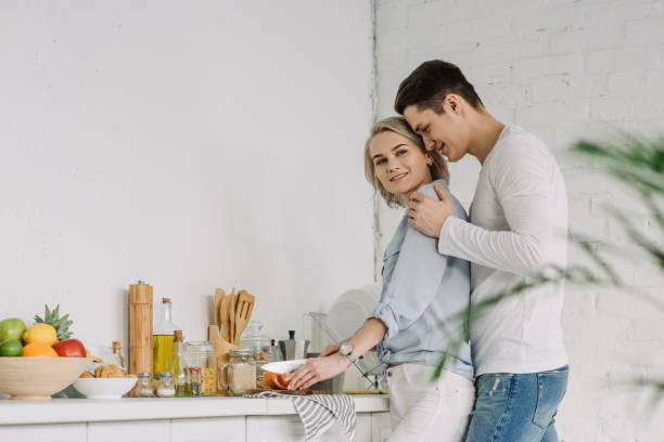 istock girlfriend cooking at kitchen and boyfriend hugging her from back 941529340