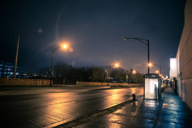 silhouette d’une personne en attente dans un arrêt d’autobus de nuit - night wet road street photos et images de collection