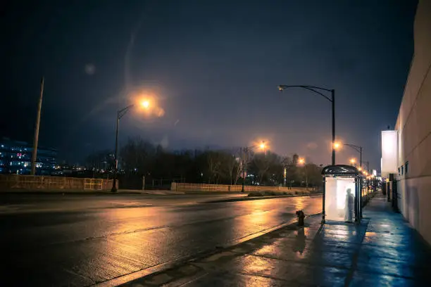 Photo of Silhouette of a person waiting in a city bus stop at night
