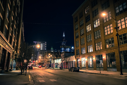 Chicago city street night scene in the West Loop with the skyline and Sears Willis Tower skyscraper in the background