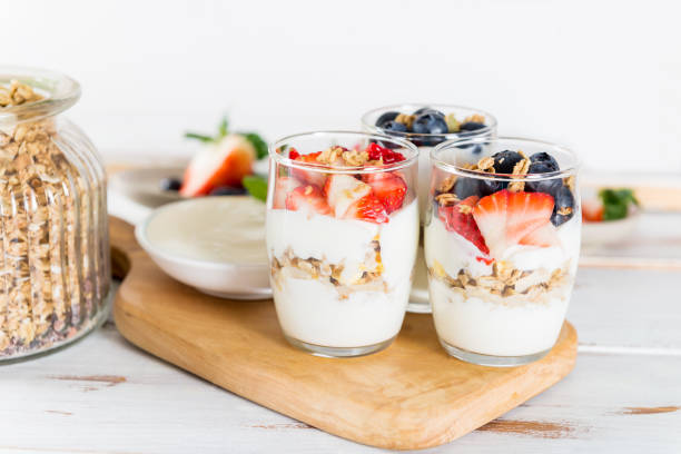 Little Jars with layered dessert from natural yogurt, granola an Little Jars with layered dessert from natural yogurt, granola and fresh strawberries and blueberries on wooden background yogurt parfait stock pictures, royalty-free photos & images