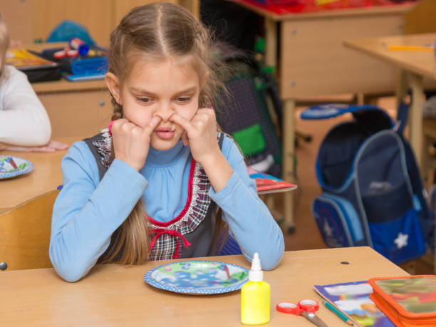 la muchacha en una lección en la escuela pegado los dedos en las fosas nasales de la nariz - picking nose fotografías e imágenes de stock