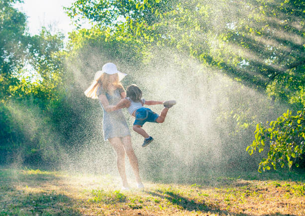 母と子が雨の中で楽しんで - wet dress rain clothing ストックフォトと画像