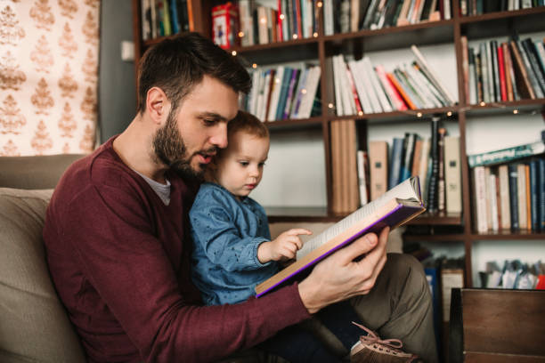 istock Father and daughter enjoying at home and reading a book 941558506