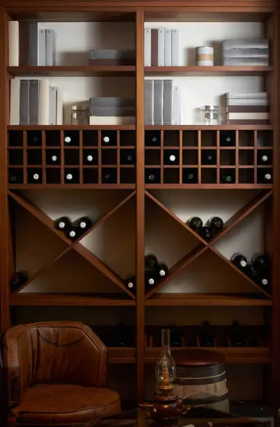 Photo of Bottles of white and red wine on a wooden shelf with books in pr