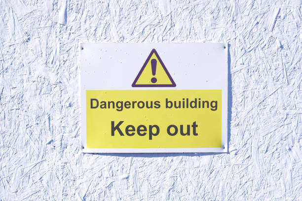istock Dangerous building keep out warning caution sign on white wall at construction building site 941563226