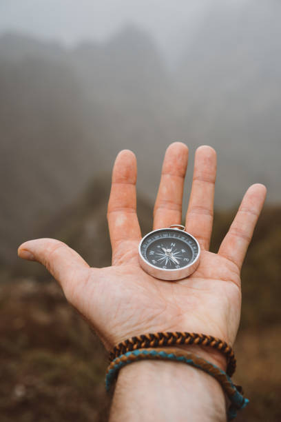 istock Hand holding a compass. Silhouette of monumental mountain formation in background 941566174