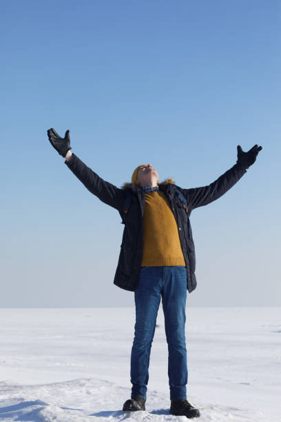 istock Man in winter clothes with hands up outdoors 941570182