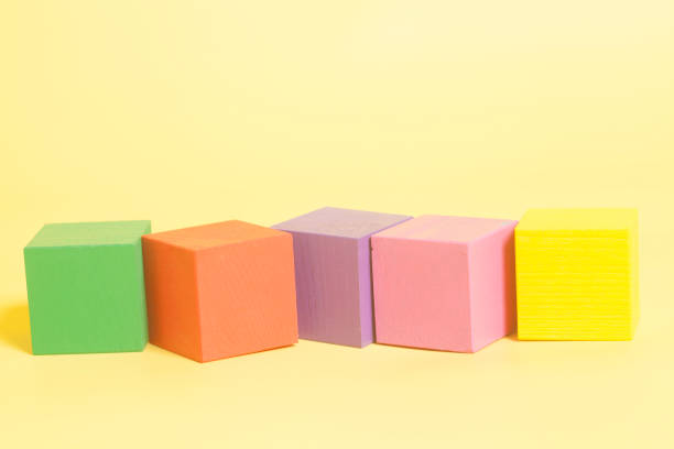 istock Coloured wooden cubes on yellow background 941570552