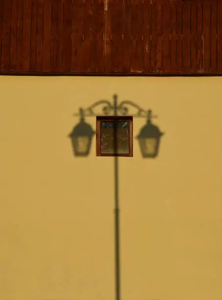 Symmetrical shadow from an old lantern on a yellow brown wall