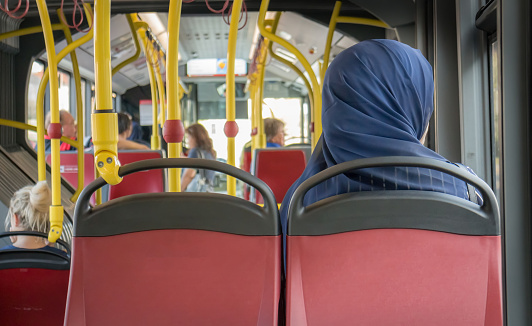 Muslim Woman sitting in the Bus wearing a scarf, public transportation  Vienna Austria August 8,2017