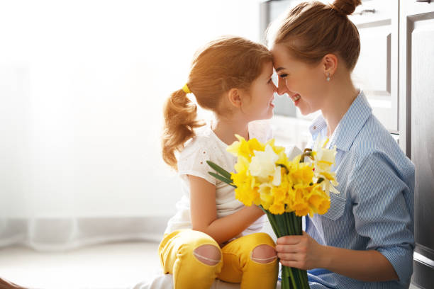 happy mother's day! child daughter   gives mother a bouquet of flowers to narcissus and gift - mother enjoyment built structure human head imagens e fotografias de stock