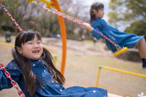 istock Little sisters playing on swing together 941590944