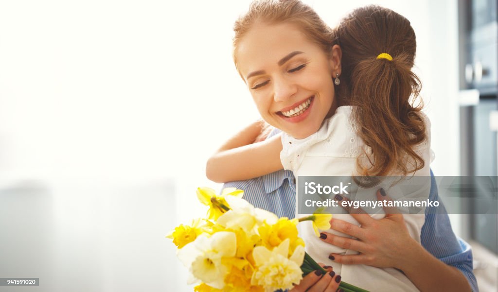 happy mother's day! child daughter   gives mother a bouquet of flowers to narcissus and gift happy mother's day! child daughter congratulates mother and gives a bouquet of flowers to narcissus and gift Mother Stock Photo