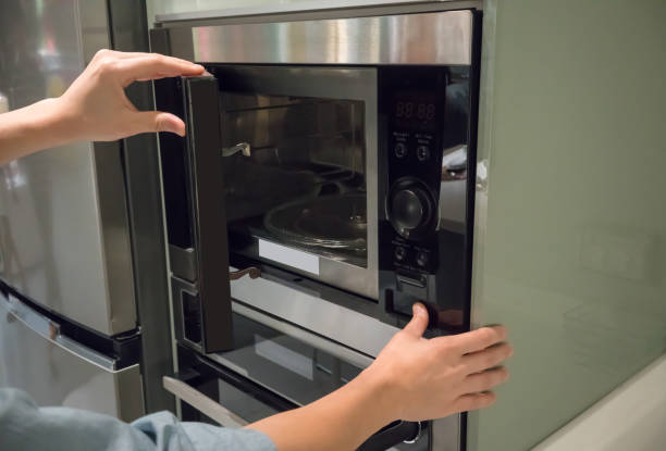 istock Woman's Hands pressing button to open microwave oven door 941591234