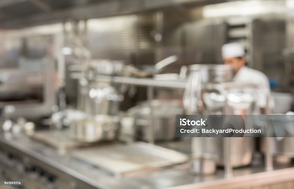 Defocused chef preparing food in commercial kitchen Defocused chef preparing food in commercial stainless steel kitchen in restaurant Commercial Kitchen Stock Photo