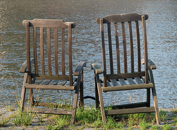 Two empty chairs at the riverbank in the afternoon sunlight.