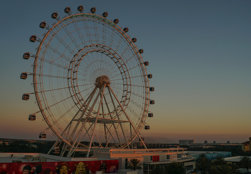 Orlando, FL, USA - March 24, 2018: The Orlando Eye on I Drive, illuminated as the sunset paints the sky orange and yellow.  The Orlando Eye is one of the newest attractions in Orlando and the largest observation wheel on the East Coast of the USA.