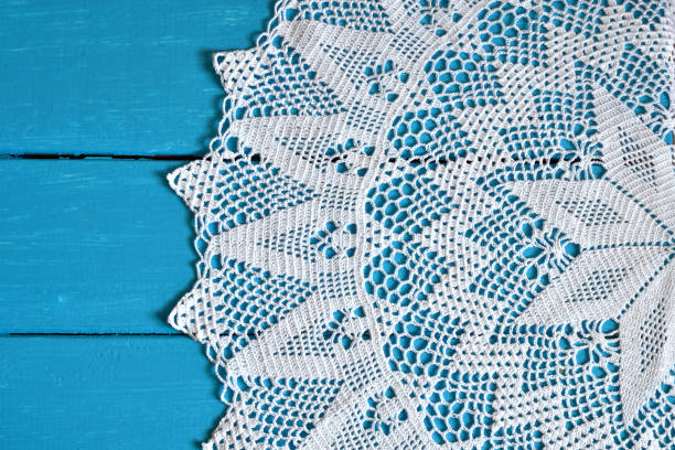 White Crochet Doily A top view image of a white crochet lace doily on a bright blue background. lace doily crochet craft product stock pictures, royalty-free photos & images
