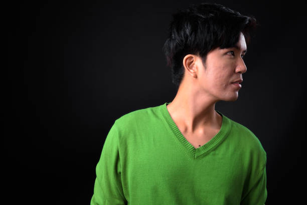 istock Young handsome Asian man against black background 941616152