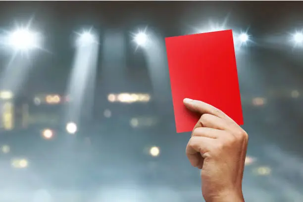 Referee hands showing red card on football match