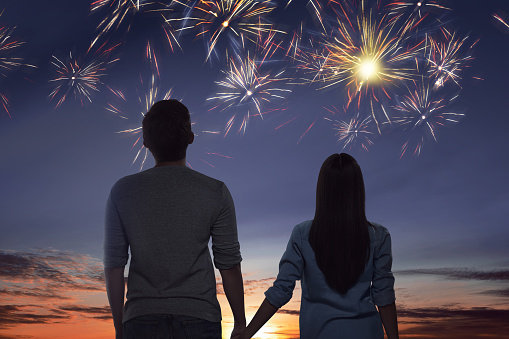 Young asian couple watching spectacular fireworks on the sky