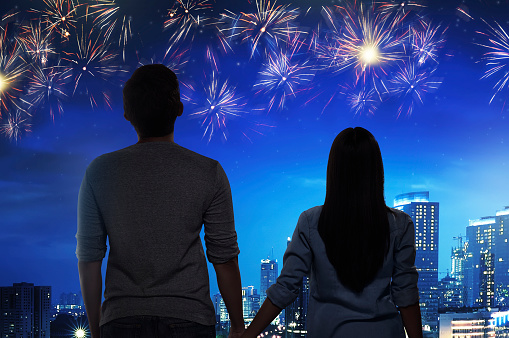 Romantic asian couple watch the fireworks together on the city at night