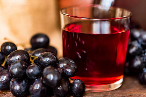 istock Red grape juice in glass and grapes close 941664808