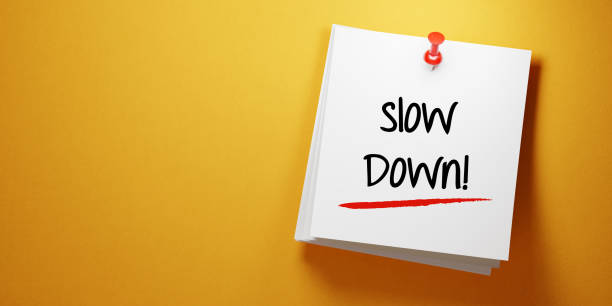 istock White Sticky Note With Slow Down Message And Red Push Pin On Yellow Background 941677256