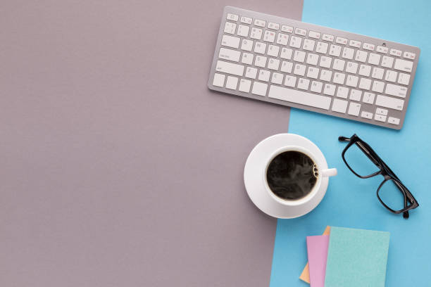 istock Desk with coffee cup and keyboard on two-colored background 941677836