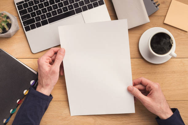istock Man holding sheet of paper at workplace 941678016