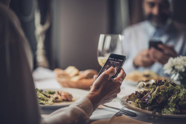 Close up of unrecognizable woman using mobile phone in a restaurant.