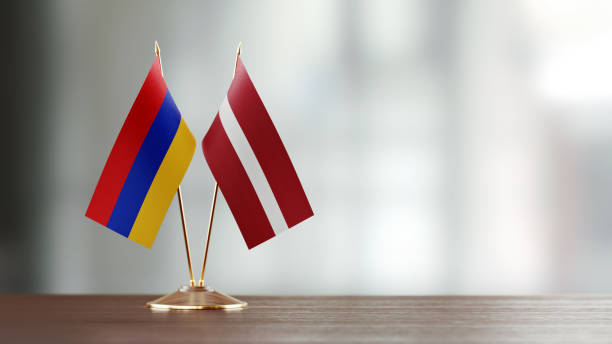 istock Armenian And Latvian Flag Pair On A Desk Over Defocused Background 941682806