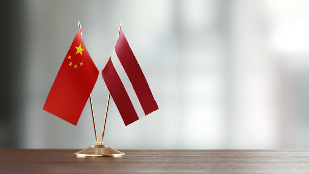 istock Chinese And Latvian Flag Pair On A Desk Over Defocused Background 941683588