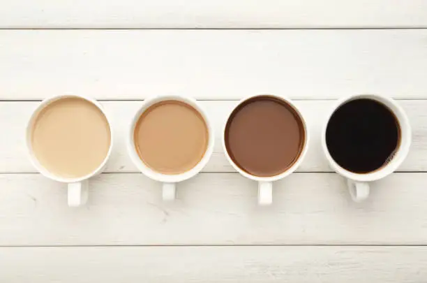 Photo of Various coffee cups on white wood, top view