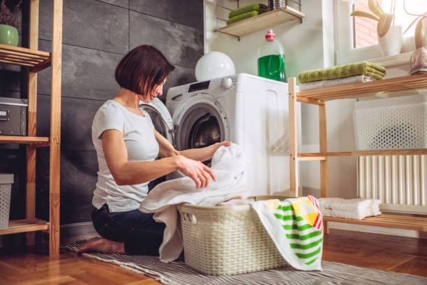 istock Woman putting clothes in a washing machine 941687022