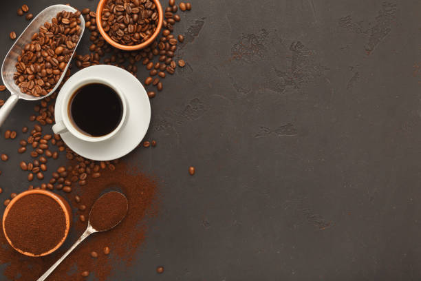 istock Cup of black coffee and scattered beans on gray background 941687444