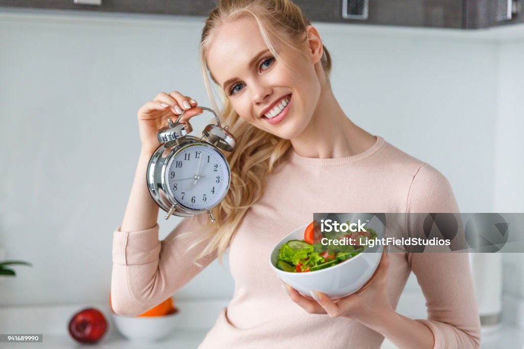 fröhliche junge Frau Holding Schüssel mit frischen, gesunden Salat und Wecker - Lizenzfrei Essen - Mund benutzen Stock-Foto