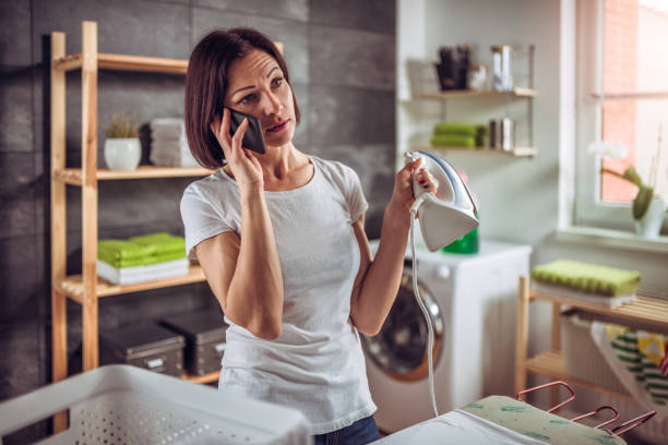 istock Woman talking on phone while ironing clothes 941690286