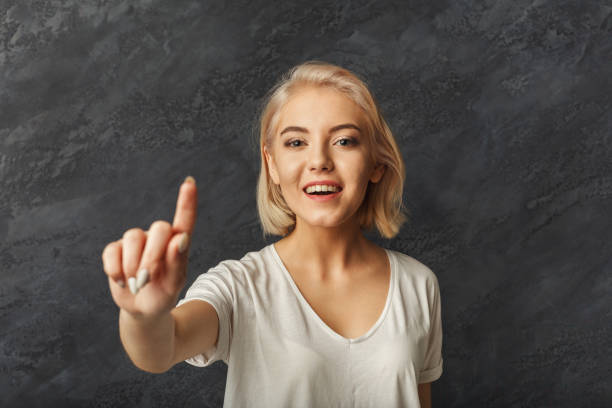 Portrait of happy woman pressing an invisible key Portrait of happy woman pressing an invisible key, camera focus on girl, copy space clicking screen stock pictures, royalty-free photos & images