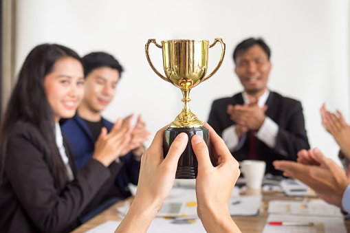 Businessman show thumbs up with trophy, reward, winner, champion and successful for business