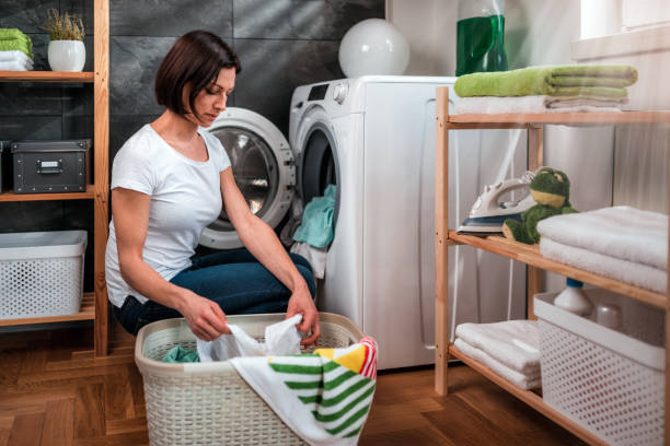 istock Woman putting clothes in a washing machine 941698390