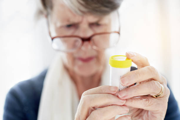 istock Old woman peering at instructions on pill container 941699108