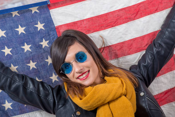 istock a young brunette with blue sunglasses in front of  american flag 941701830