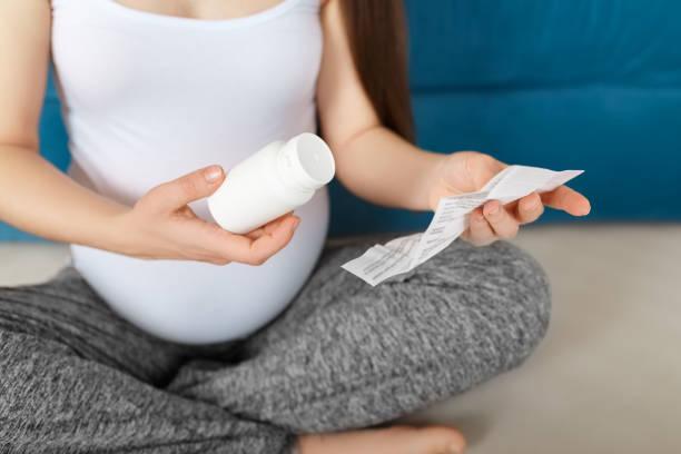 pregnant woman holding bottle of pills stock photo
